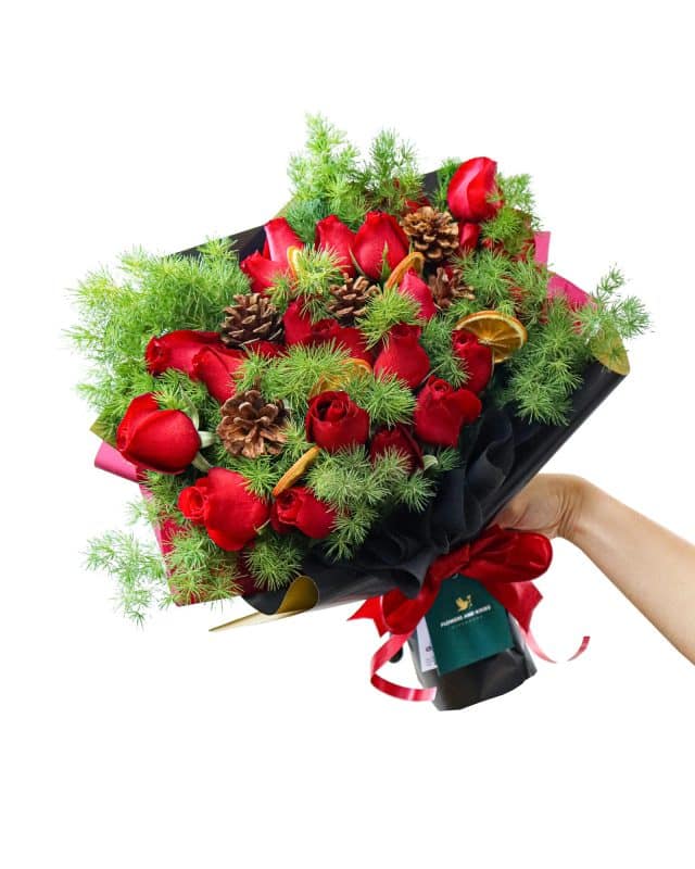 A festive Christmas bouquet of red roses, pine cones, preserved orange slices and ming fern from Singapore florist Flowers and Kisses 